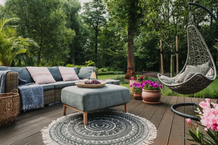 Outdoor rug placed under patio furniture on gravel backyard.