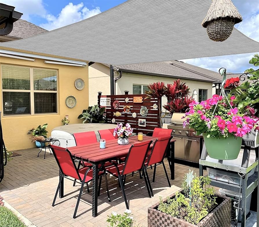 Backyard patio with shade sail and seating area on gravel without grass.