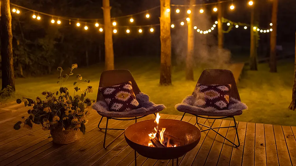 Beautiful no-grass backyard with gravel, seating area, fire pit, and string lights. (Cheap Backyard Ideas No Grass)