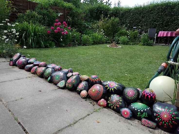 Painted rock border separating gravel and plant areas in backyard.