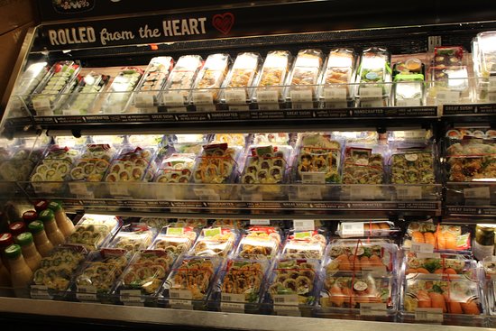 Prepackaged sushi trays displayed in a grocery store refrigerated case. (cheap sushi near me)