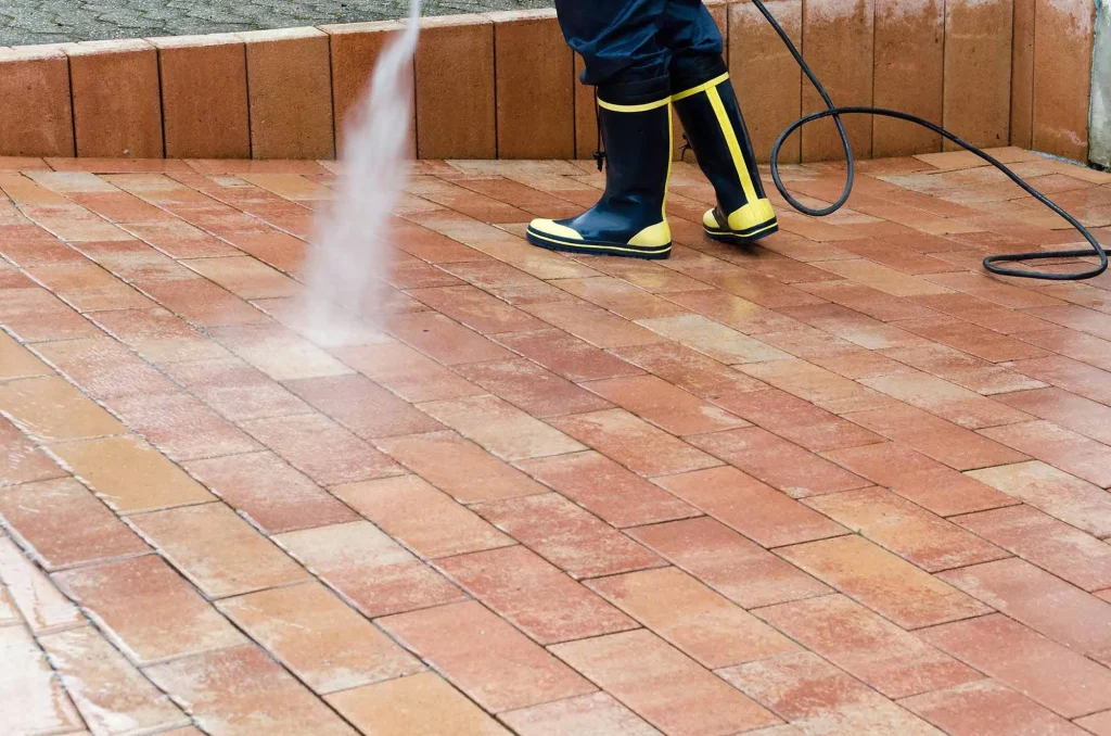 Cleaning and pressure washing backyard pavers in no-grass yard.
