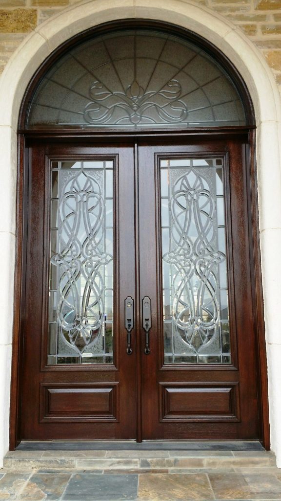 Exterior double doors featuring decorative and frosted glass panels for natural light