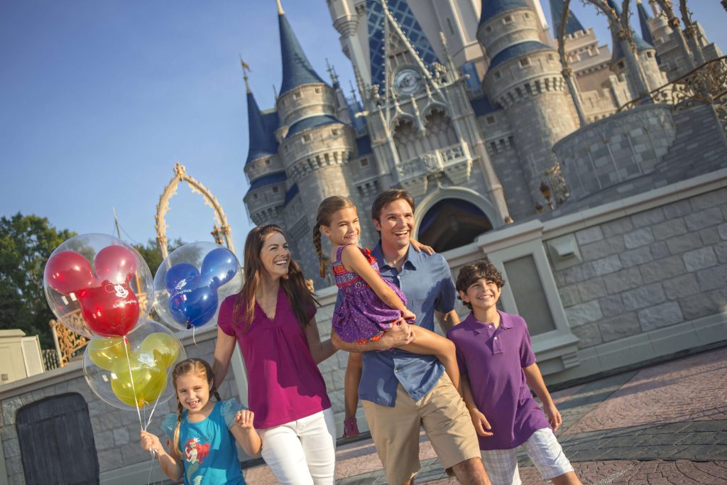 Happy family with balloons walking toward Cinderella's Castle at Magic Kingdom.