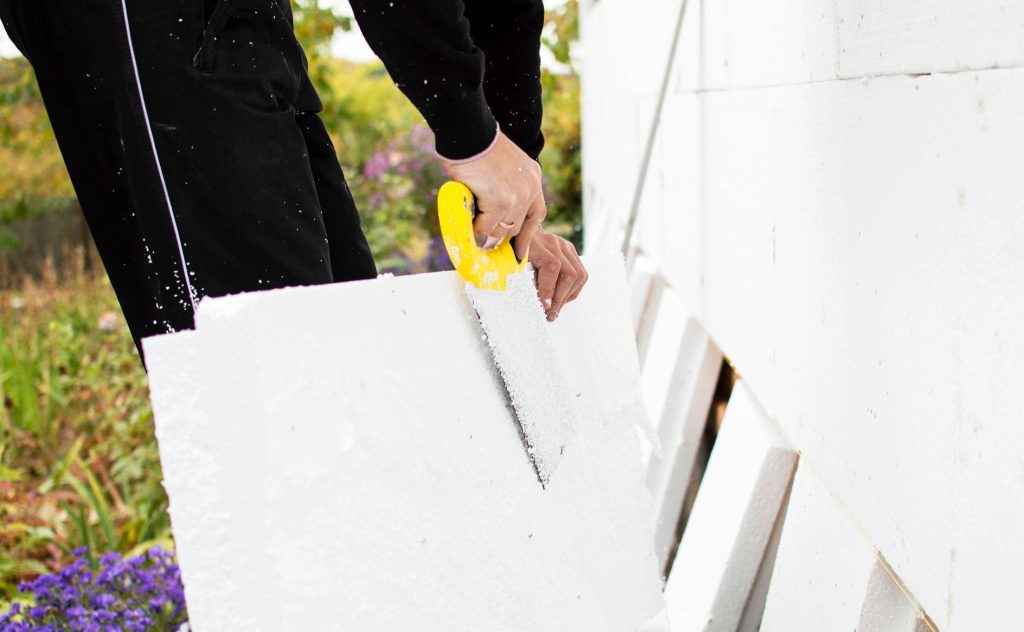Homeowner installing foam board insulation on basement walls
