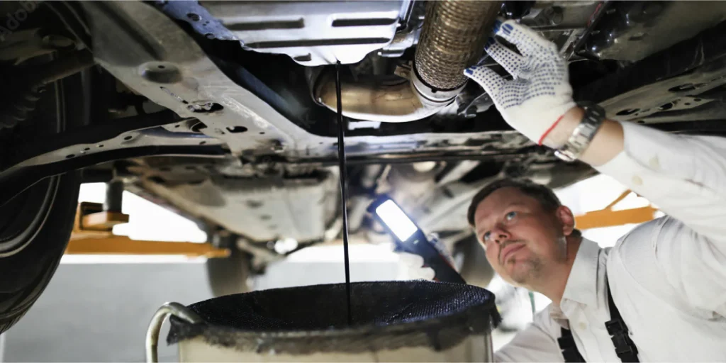 Mechanic draining engine oil during service
