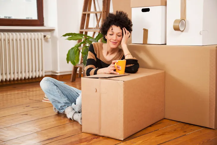 Person overwhelmed by boxes in small studio apartment
