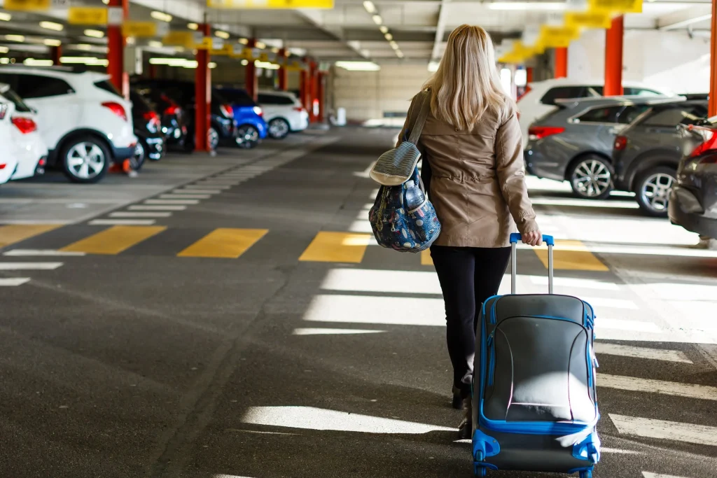 Traveler walking toward airport terminal from parking lot. (Cheap Airport Parking Promo Code)