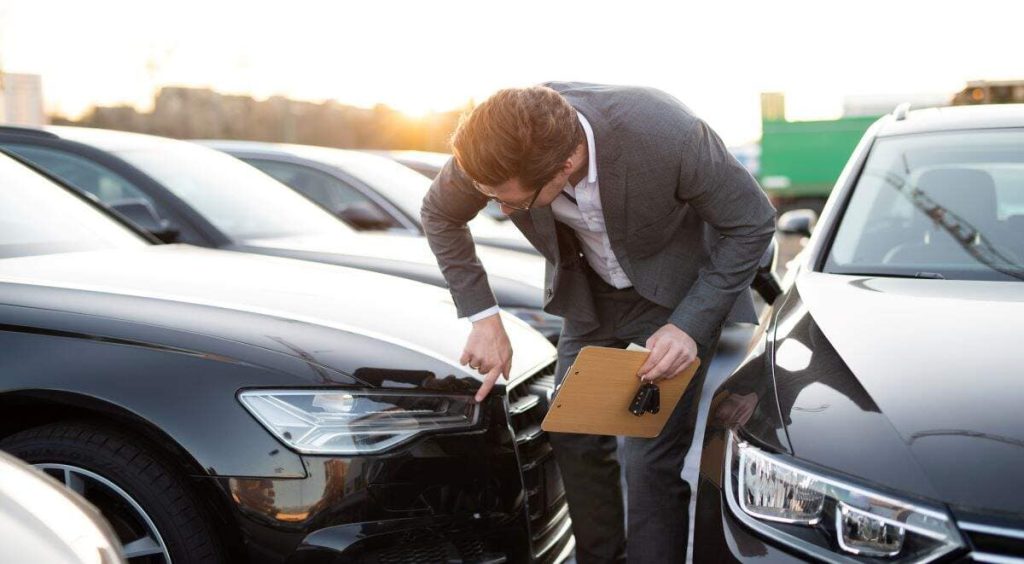 college student inspecting a cheap used car before buying