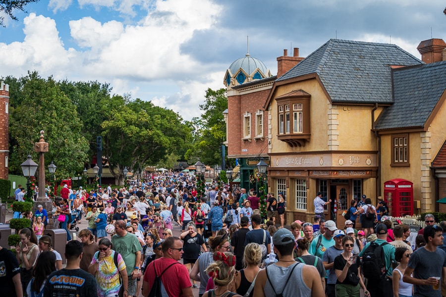 Busy crowd walking through Epcot at Disney World on a sunny day.