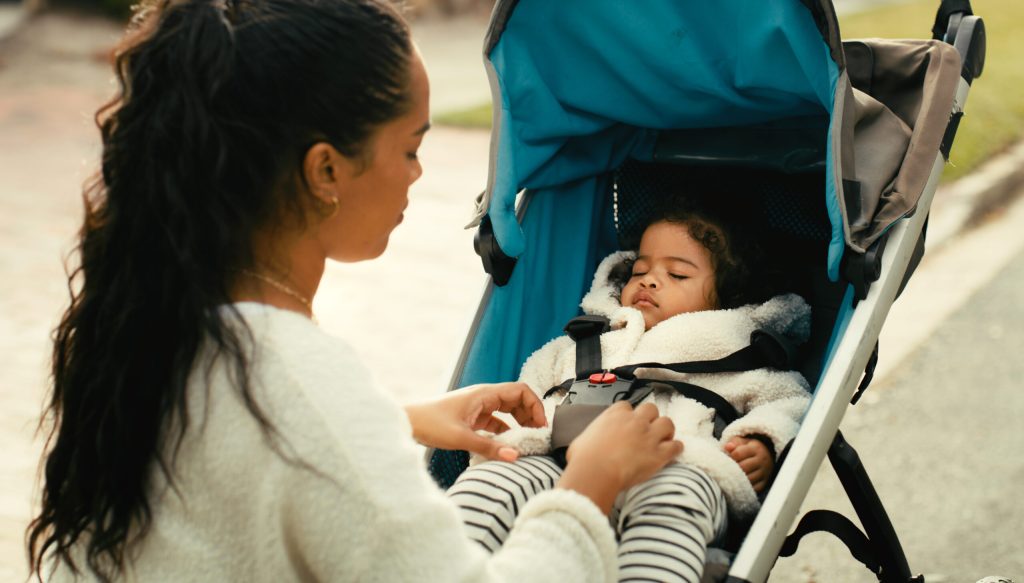 Parent checking a stroller harness before use